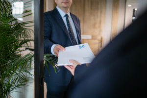 tors mężczyzny w garniturze podającego teczkę z dokumentami innej osobie